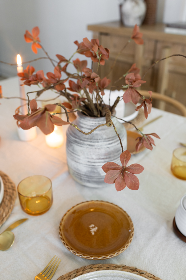 Fall table decor lit by warm candlelight for a cozy gathered dinner