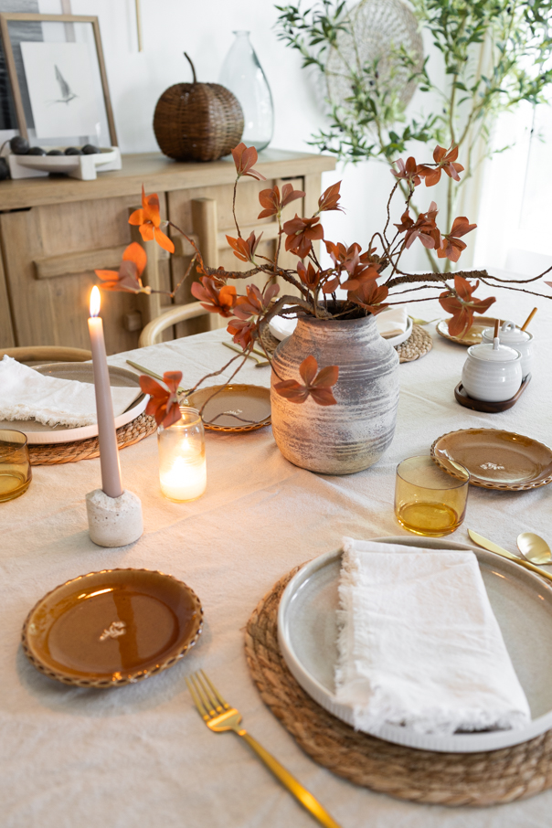 Warm taper candles adding height and glow to a simple fall table setting