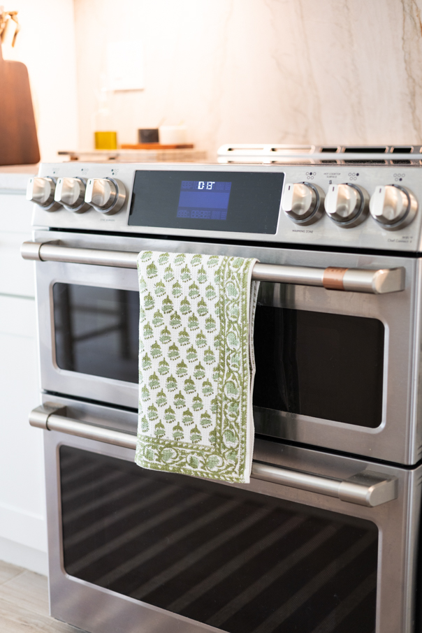 Green earthy Fall kitchen towel hanging over a oven