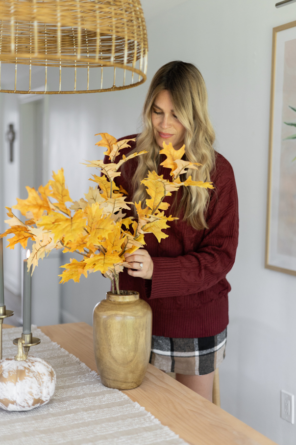 Andi arranging fall faux stems in a vase